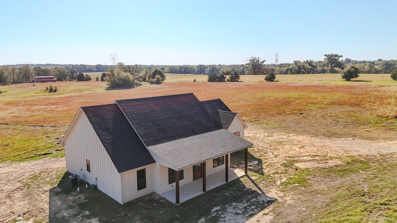 farmhouse style modern home in open field with sunset sky | GPS: 33.136168, -95.223265